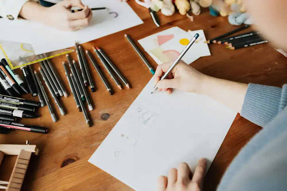 An artist's desk with scattered botanical sketches, pencils, and plant cuttings