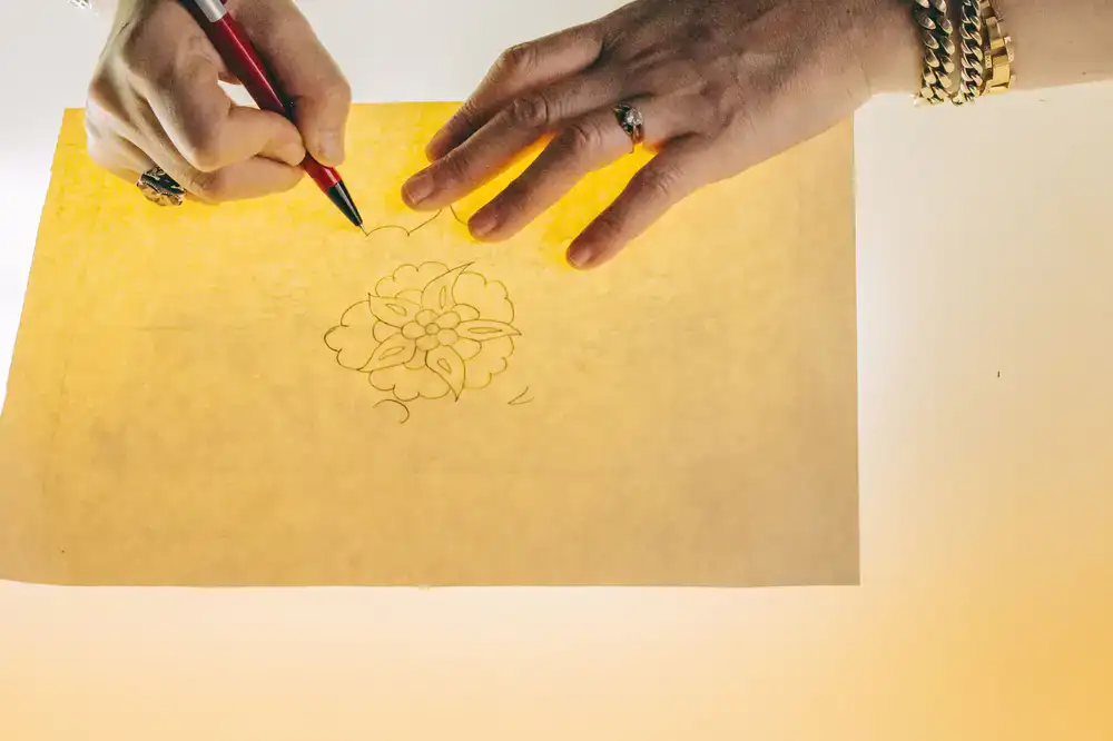 Artist's hands sketching a leaf on premium paper